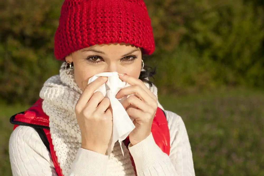 Frau mit Erkältung und Taschentuch